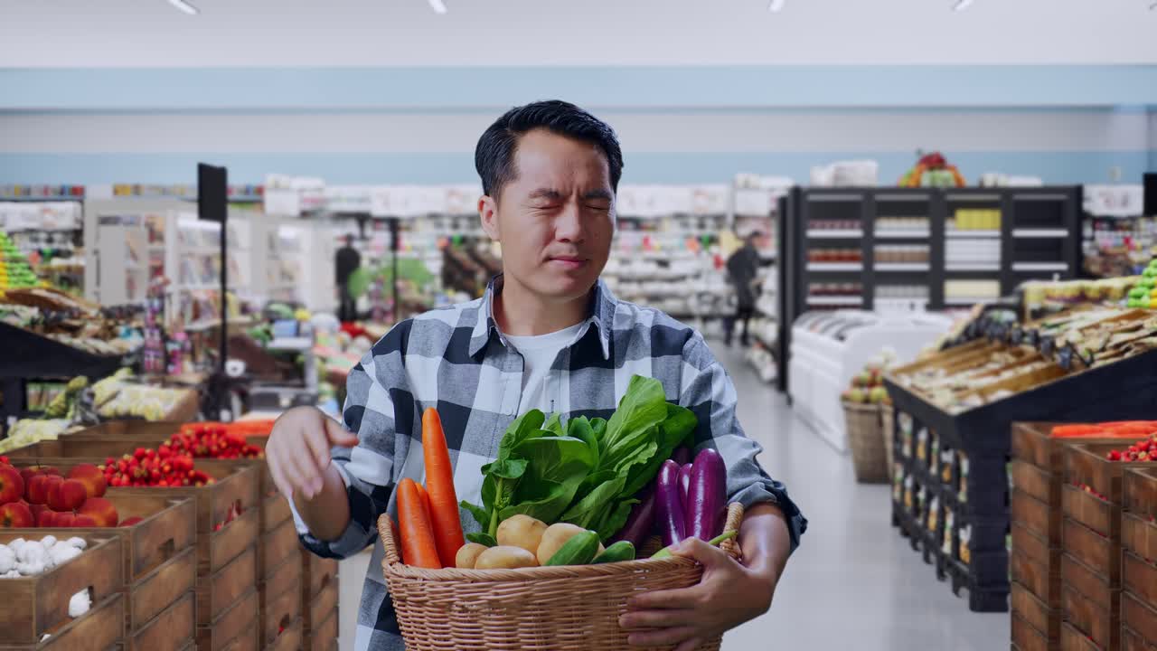 Agricultor asiático cansado con una cesta de verduras de pie en un supermercado