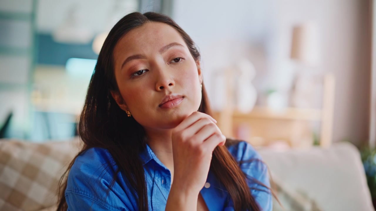 Depressed asian woman covering face home sofa. Close up worried female portrait.