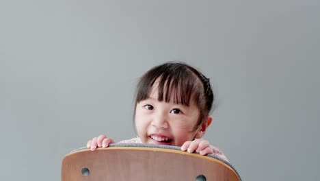 Child-playing-on-the-chair-at-home-and-looking-at-camera