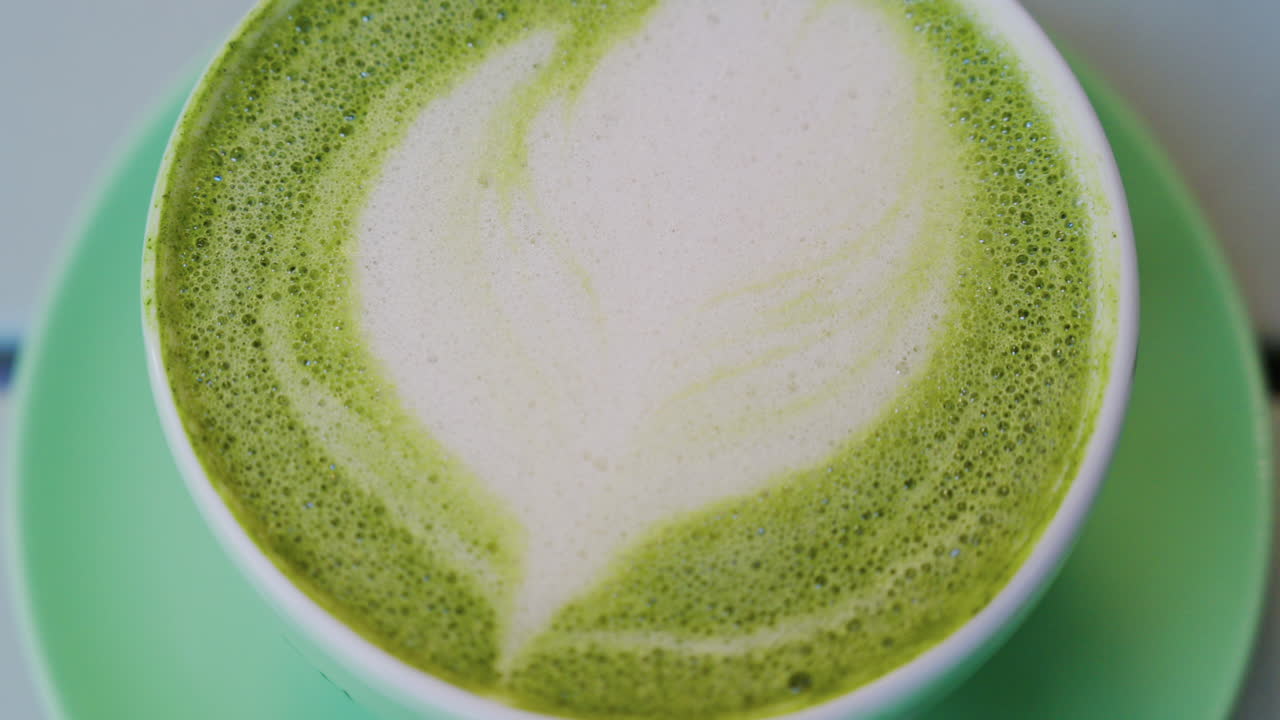 Close up of a matcha latte in a green cup on a terrace table