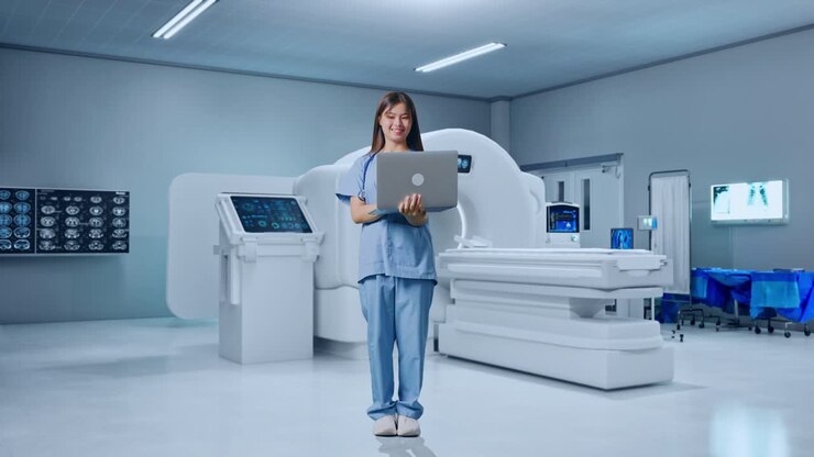 Figura intera di dottoressa asiatica che digita su un laptop accanto a una macchina per la risonanza magnetica