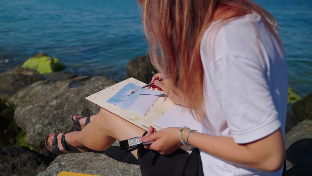 mujer pintando acuarela paisaje marino en la playa