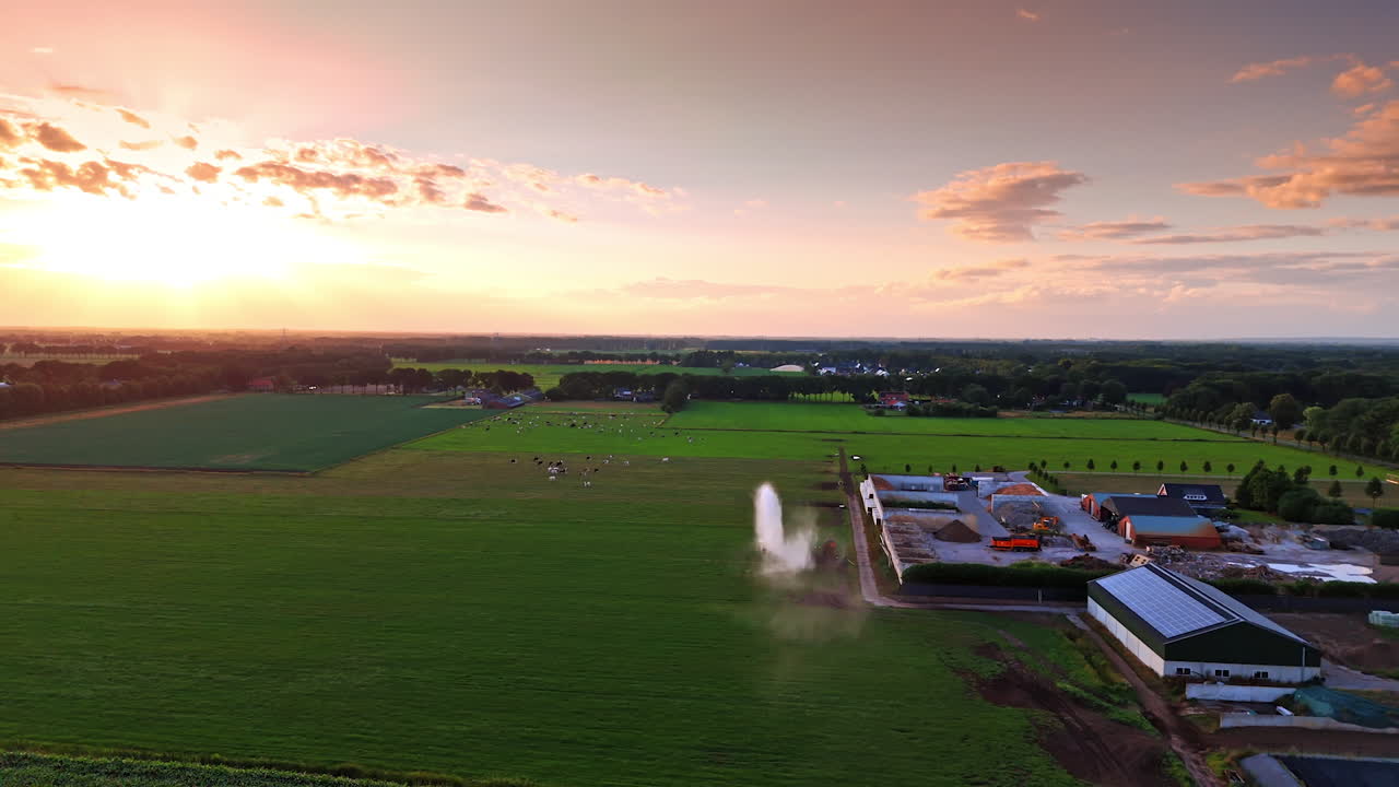 Tramonto su pascoli agricoli. Un tramonto pittoresco illumina un paesaggio rurale con bestiame al pascolo in lontananza ed edifici agricoli nelle vicinanze.