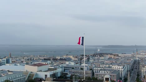 majestuosa órbita aérea suave redonda bandera francesa con el horizonte de la ciudad de brest, francia en el fondo