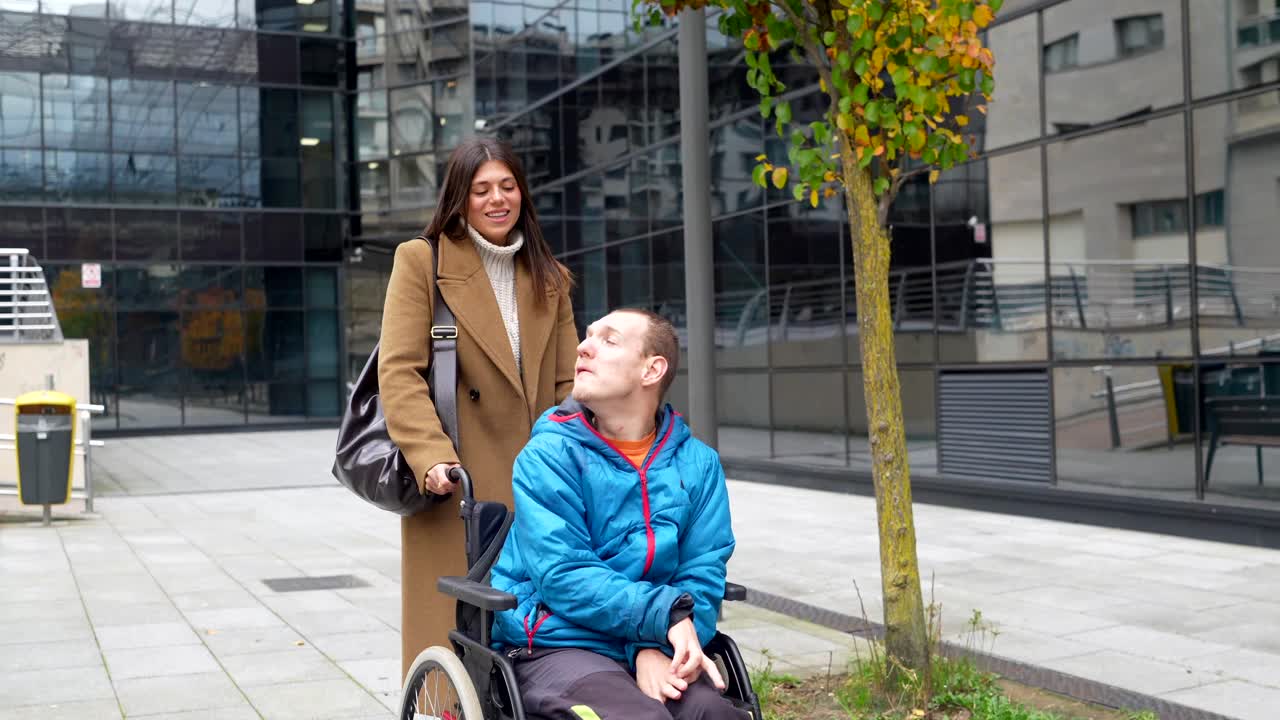 Donna che assiste un uomo in sedia a rotelle all'aperto