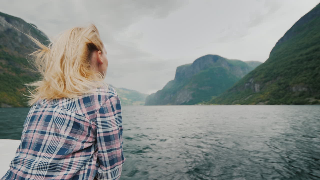 A Romantic Woman On The Bow Of The Ship Sailing Along The Beautiful Fjord The Wind Blows Into Her Ha