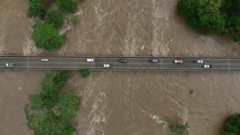 bird's-eye view over cars driving across the raging barron river, cairns