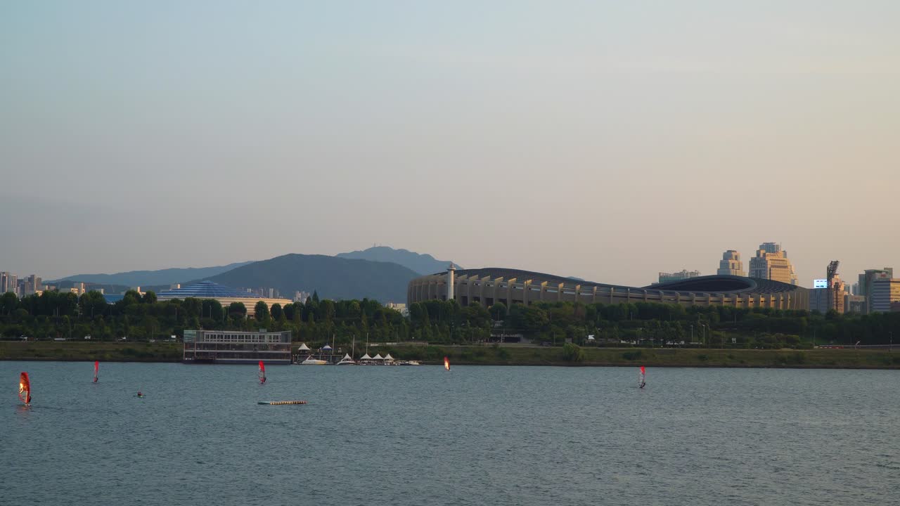 뚝섬공원, 잠실종합운동장, 잠실경기장, 멀리 떨어진 산들 등에서 일몰을 배경으로 한강에서 윈드서핑을 즐기는 사람들 - 광각 복사공간