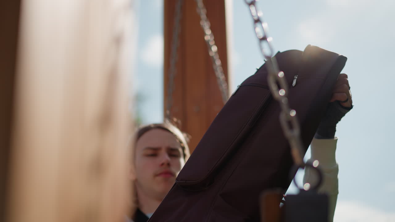 GrajÄ…cy na biaÅ‚ej gitarze mÄ™Å¼czyzna stroi gitarÄ™ akustycznÄ… na zewnÄ…trz, na huÅ›tawce na podwÃ³rku. Skupiony wyraz twarzy, gdy palce regulujÄ… koÅ‚ki stroikÃ³w. Delikatne Å›wiatÅ‚o sÅ‚oneczne i bryza. ZbliÅ¼enie na gryf i struny. Muzyk przygotowuje siÄ™