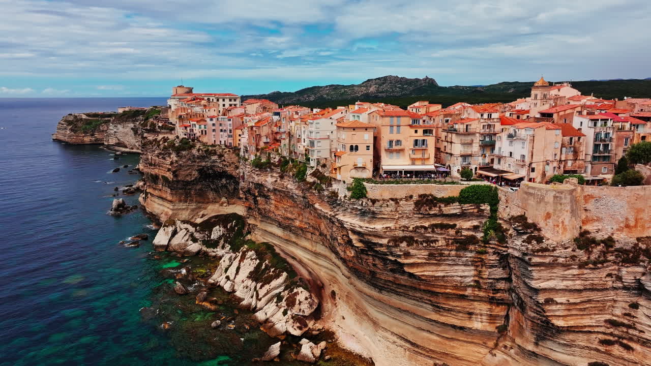 Aerial drone shot over the historic coastal town of Bonifacio in Corsica, France. High view of the rocky steep cliff and the turquoise sea. Ancient Citadel overlooking the rugged coastline