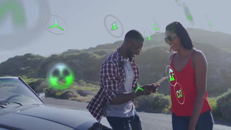 animación de íconos de la energía y la ecología sobre una feliz pareja diversa en coche en un viaje por carretera