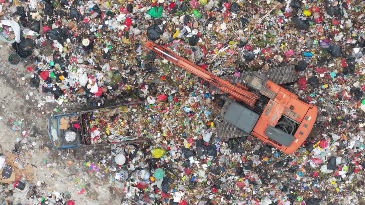 Escavatore al lavoro in una discarica di rifiuti, inquinamento.