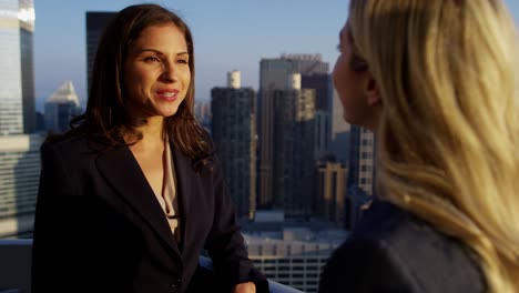 handshake between multi ethnic businesswomen on city rooftop
