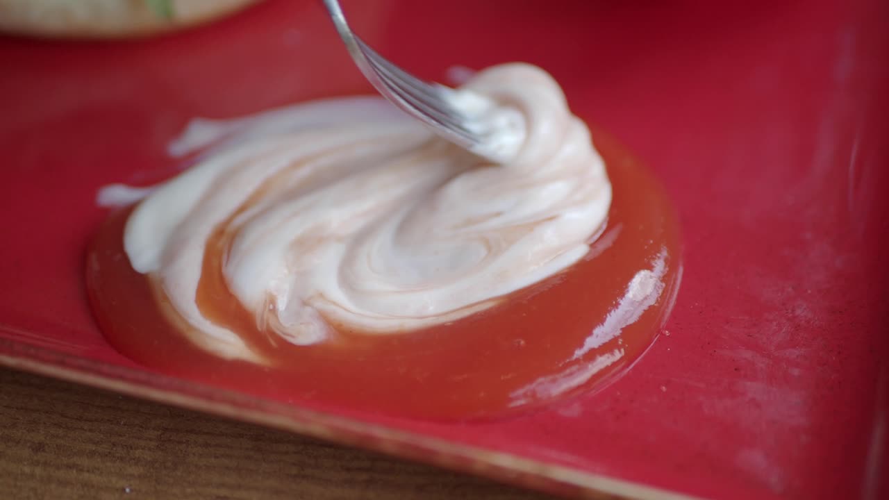 Sauce being mixed with a fork on a red plate