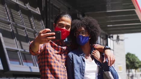 Diverse-colleagues-wearing-face-masks-taking-selfie-using-a-smartphone