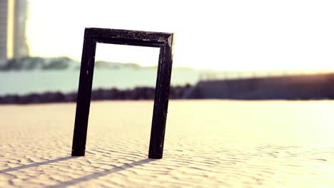 black frame standing on sandy beach with sunlight casting long shadows