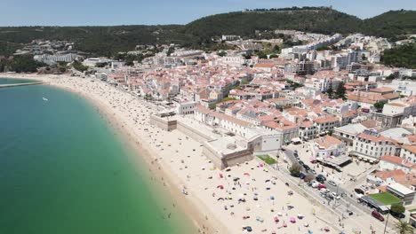 Playa-De-Sesimbra-Llena-De-Turistas-Durante-Las-Vacaciones,-Disparo-De-Drones-Orbitales-Aéreos