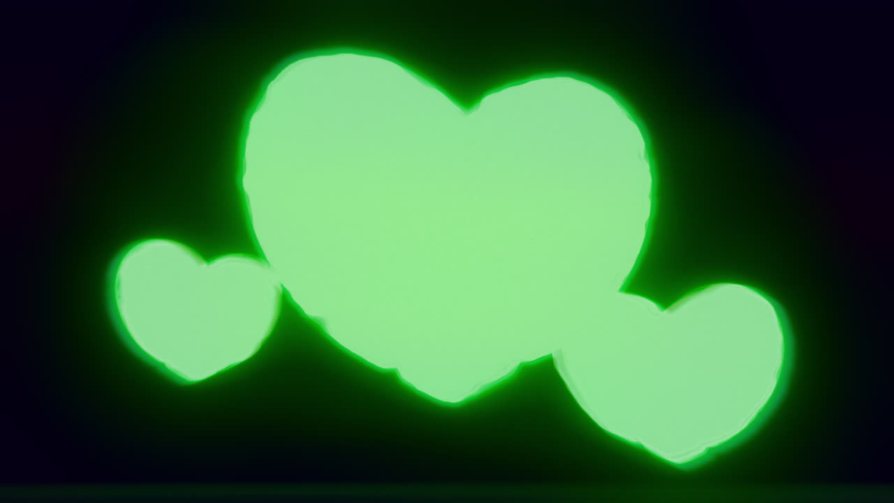 Green energy heart shapes on a dark background