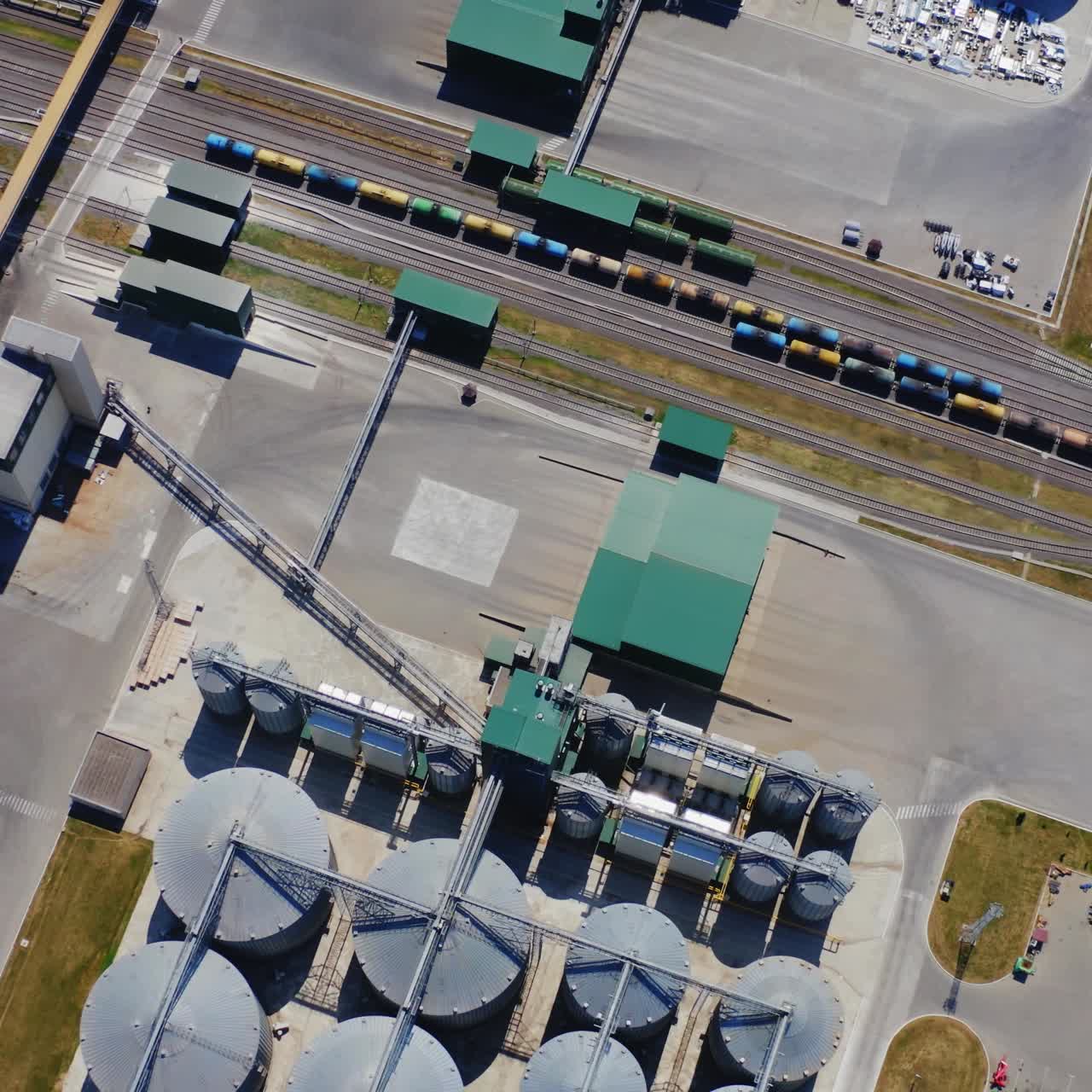 Exterior of agricultural silos for grains. Flight over industrial territory with elevators in the countryside. Freight carriages near the granary. Aerial view.