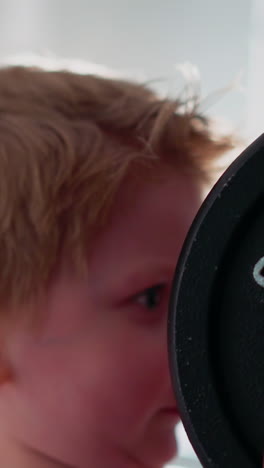 concentrated little boy lifts heavy barbell with hands against bright lamp illuminating gym. toddler wants to be real sportsman doing exercise with weight closeup slow motion