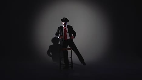 man in a fedora and suit under spotlight