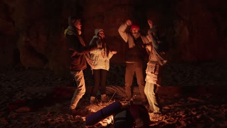 friends dancing around a campfire on a beach at night