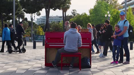 street musician playing red piano in a public park