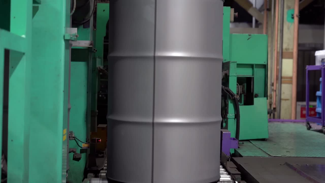 los tambores de acero viajan constantemente en un transportador para su posterior procesamiento