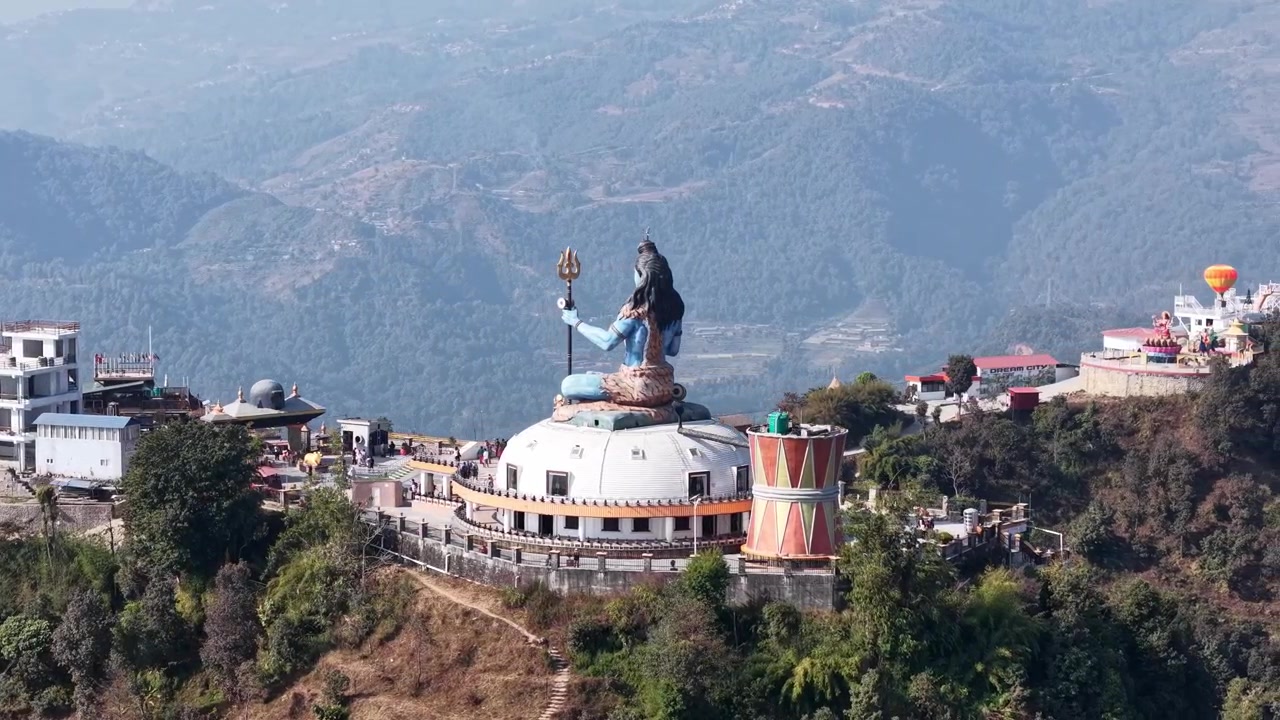 Imagem aérea de drone do icónico monumento de Shiva e dos edifícios de templos circundantes numa crista verde em Pumdikot.
