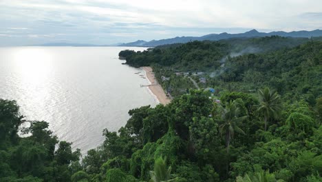 Aerial-ascent-over-rainforest-and-small-coastal-village,-Cataduanes,-Philippines