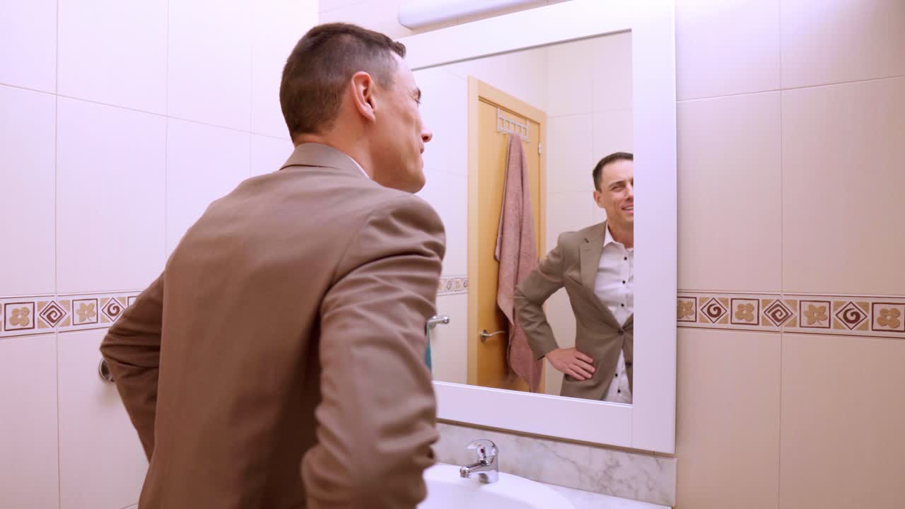 Elegant businessman checking his look in bathroom mirror