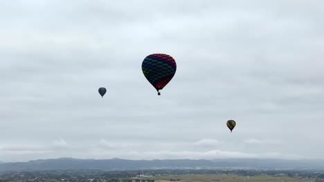 aerial around multiple hot air balloons on overcast day in temecula