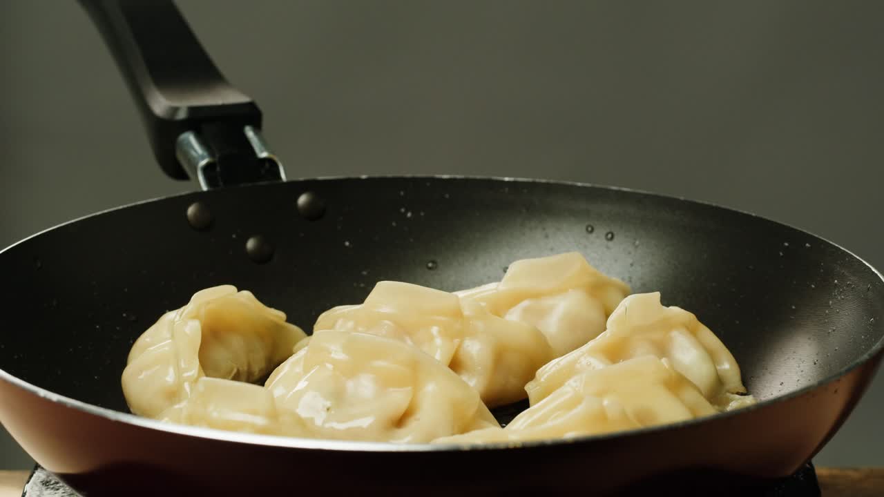 Close-up of Steaming Dumplings Frying in a Hot Pan