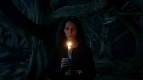 woman holding a lit candle in a dark, mysterious forest