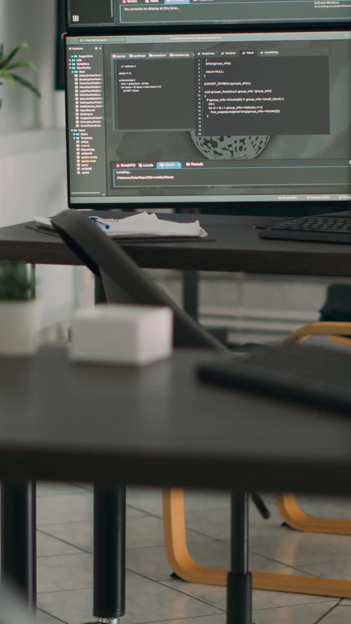 Video i højformat: Tomt skrivebord med flere skærme, der viser serverkode og programmeringssprog