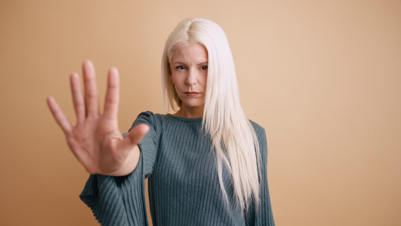 Serious Woman Making Stop Hand Gesture in Studio