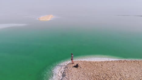 view of the beach at resort village of ein bokek. view from top. aerial view. young man walking on the shore of the dead sea.