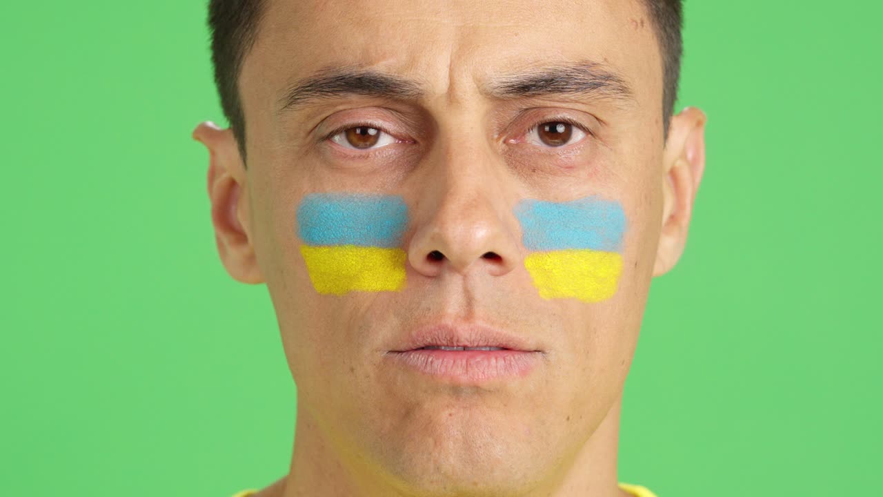 Man with a ukrainian flag painted on the face smiling