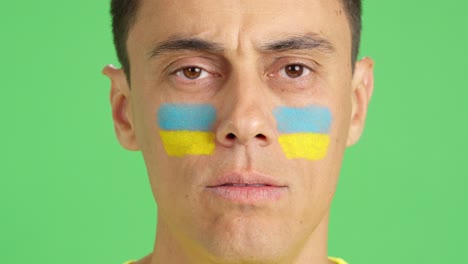 man with a ukrainian flag painted on the face smiling