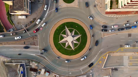 drone top-down view of cars moving around modern wind rose roundabout in genoa, italy in daylight