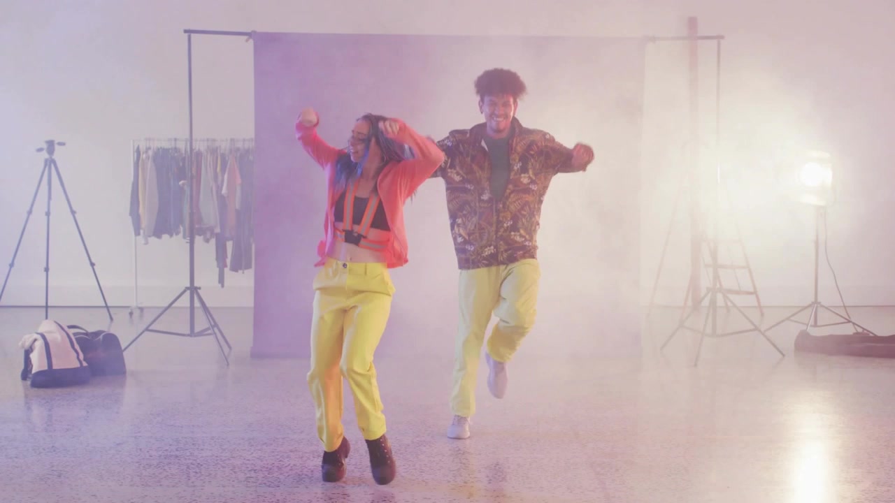 Front dancer stepping and leading dance, rear dancer mirroring while glitch sweeping obscuring them