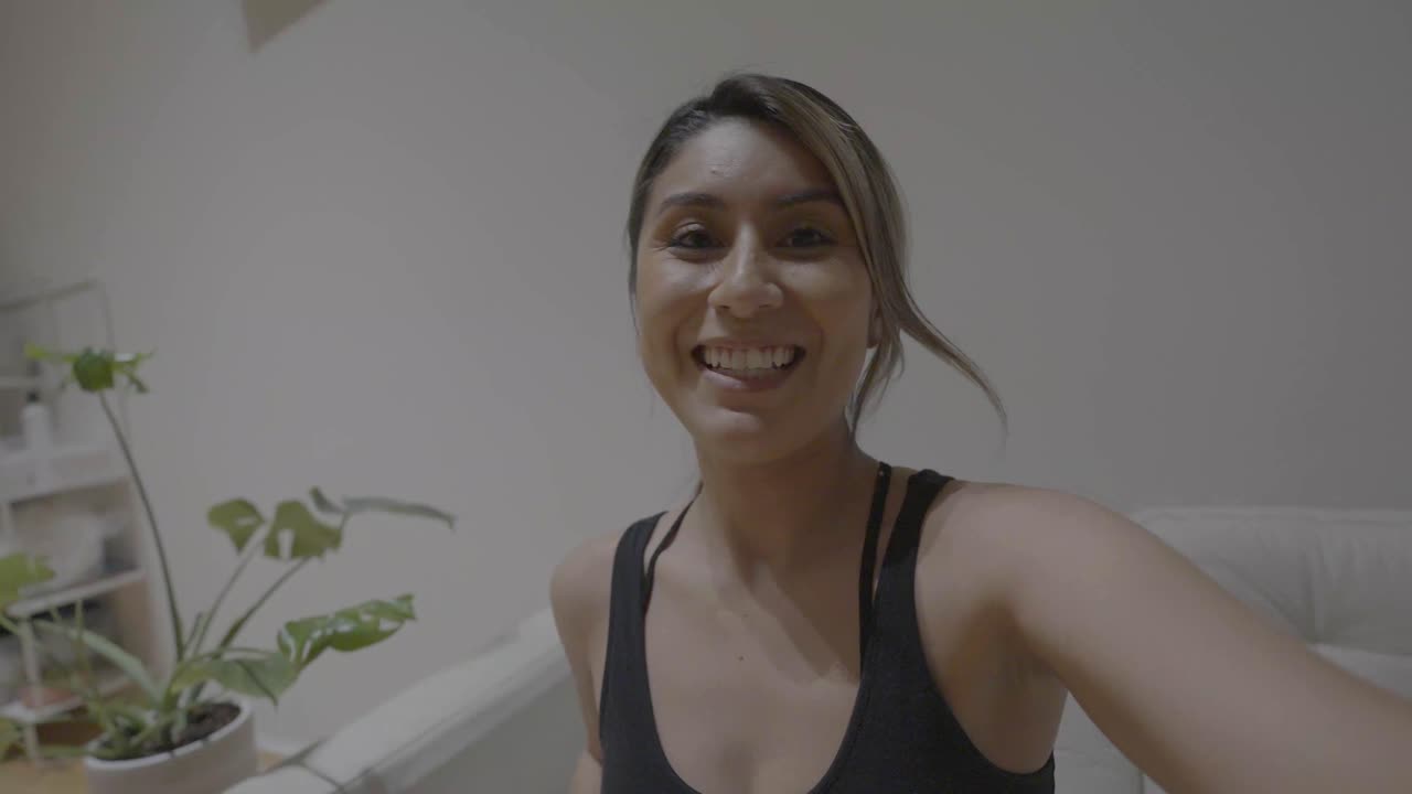 una mujer hispana despidiéndose de sus amigos a través de su dispositivo en línea