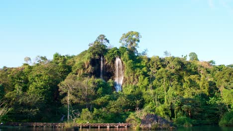 una amplia vista de la cascada natural que fluye por la montaña está iluminada por el sol vespertino