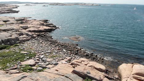 aerial pull out shot capturing the unspoiled calm shimmering blue sea and barren rocks against the open horizon in summer, bohuslan coast, sweden