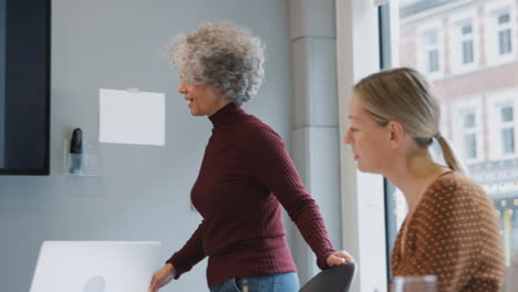 Empresaria-Madura-Liderando-Una-Reunión-Creativa-De-Mujeres-Colaborando-Alrededor-De-Una-Mesa-En-Una-Oficina-Moderna