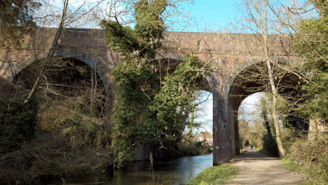 pan along high arched brick railway bridge crossing a shallow stream in the countryside