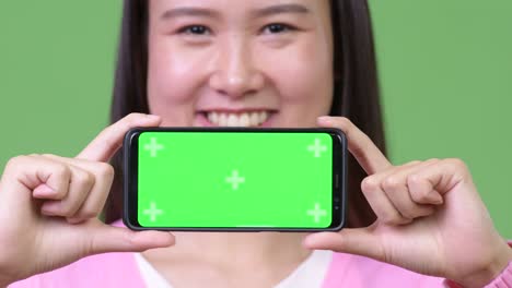 Young beautiful Asian woman showing phone