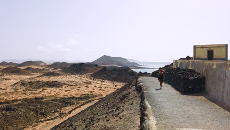 a woman walking on a pathway with a scenic view of los lobos island