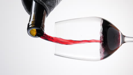 verter vino tinto en copa de vino sobre fondo blanco, video vertical