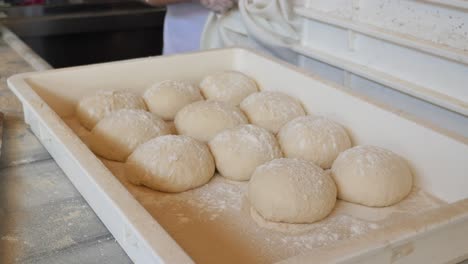 close up of dough balls on a white tray in a bakery